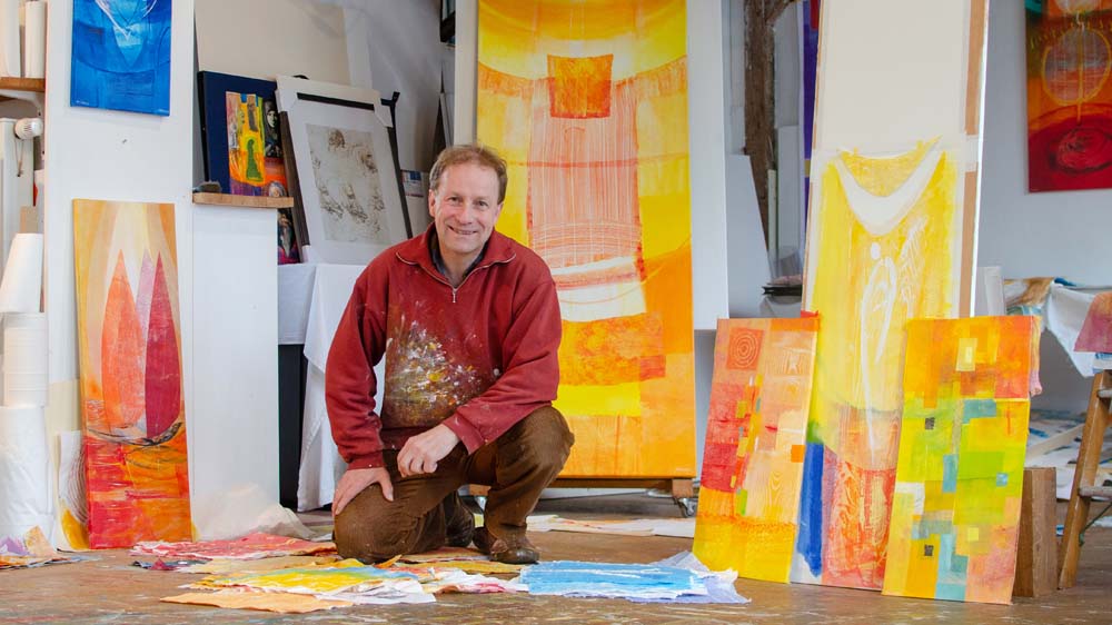 Jörgen Habedank in seinem Atelier vor bunten Gläsern