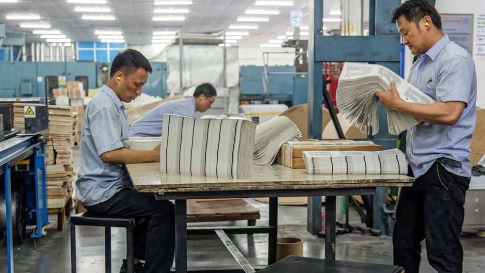 Arbeiten ordnen Papierbögen in der Druckerei Amity Printing Company