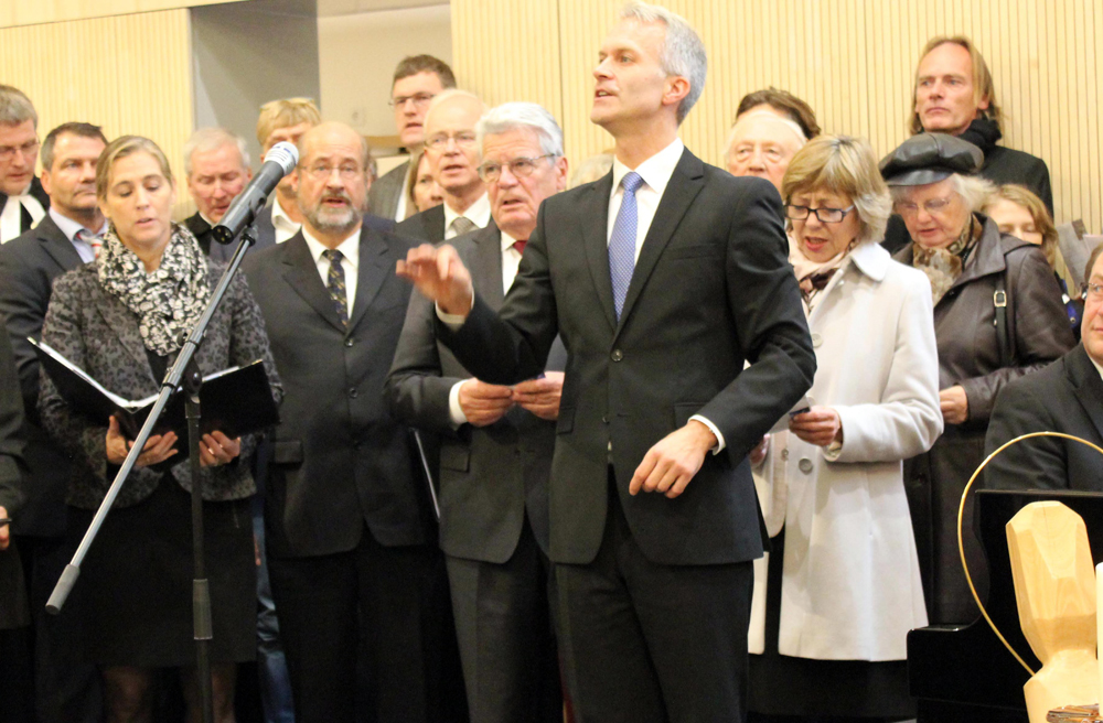 Kantor Markus J. Langer dirigiert, Bundespräsident Gauck und seine Lebensgefährtin singen im Hintergrund mit