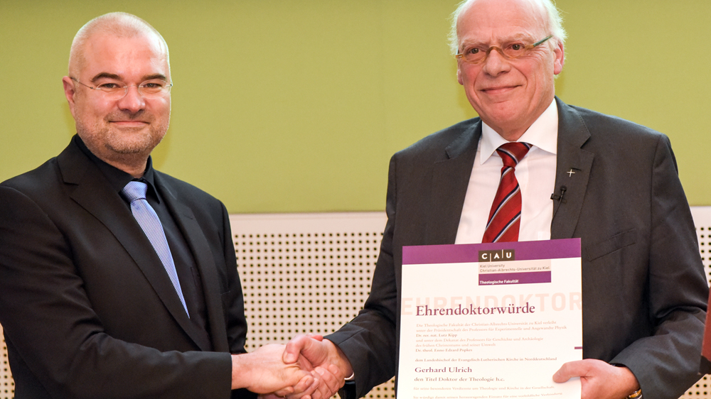 Der Dekan der Theologischen Fakultät, Professor Enno Edzard Popkes, übergibt die Urkunde an Dr. h.c. Gerhard Ulrich
