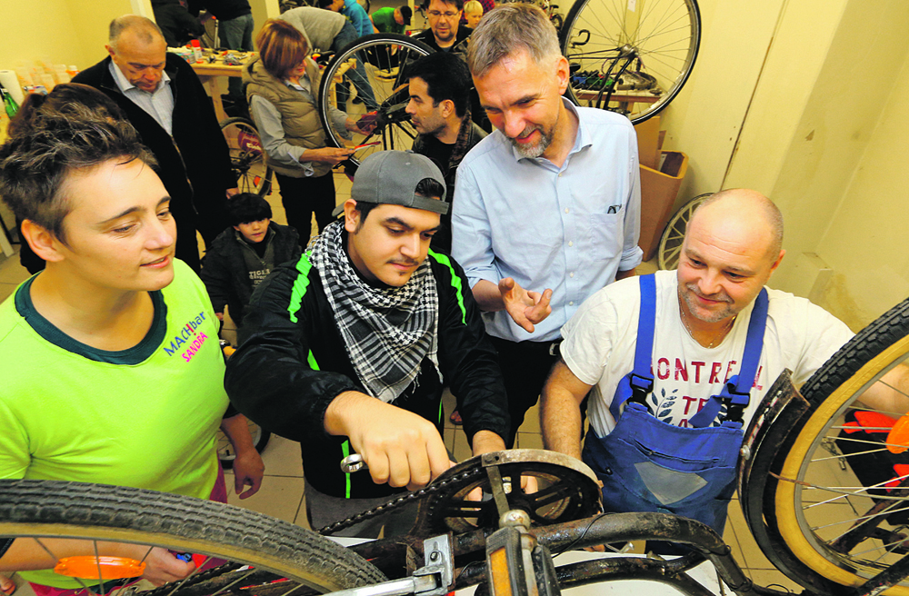 In der Fahrradwerkstatt: Bischof Jan Janssen (zweiter von rechts) mit Flüchtlingen