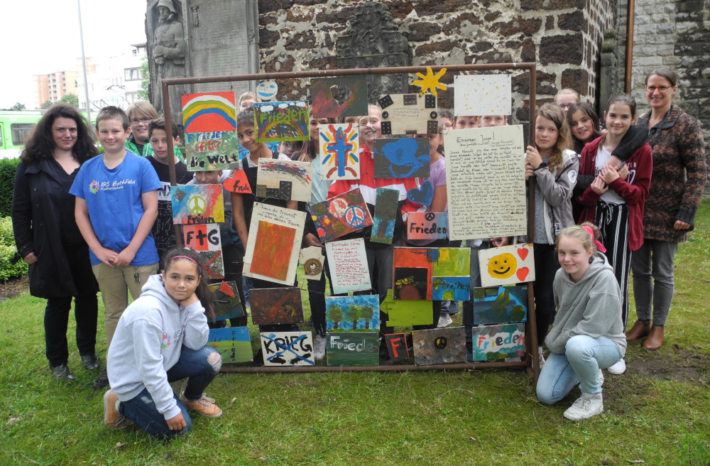 Schüler der IGS Bothfeld präsentieren gemeinsam mit Lehrerin Astrid Ziron (links) und Künstlerin Almut Breuste (rechts) das Friedensmahnmal.