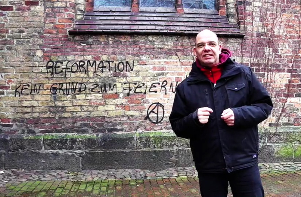 Stadtpastor Johannes Ahrens vor dem Graffiti an der St.-Marien-Kirche in Flensburg