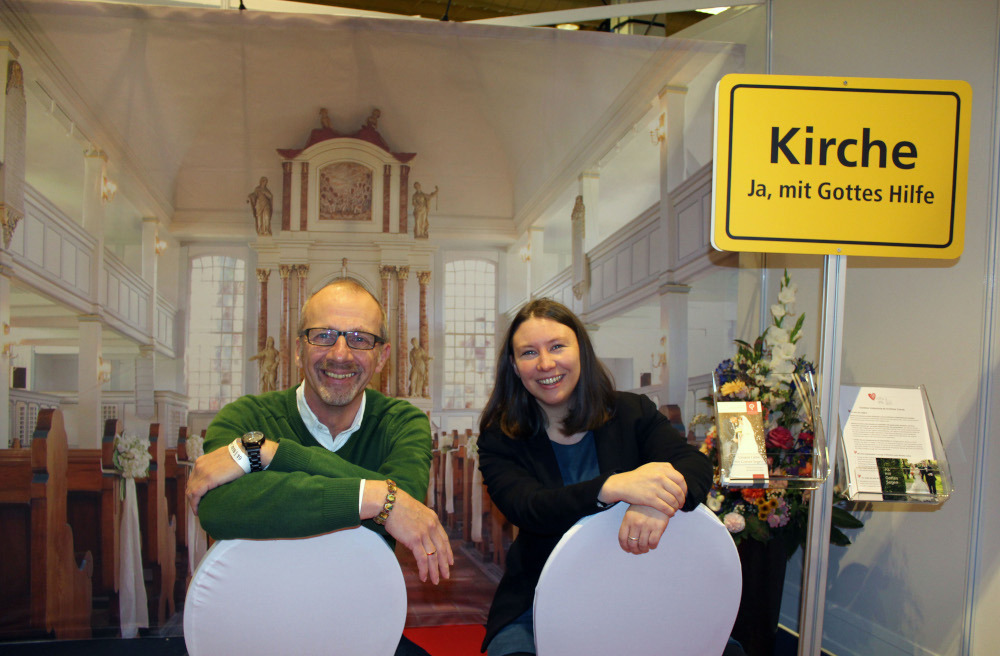Laden zum Probesitzen ein. Auf der Hochzeitsmesse testen Vikarin Linda Pinnecke und Pastor Michael Ellendorff vor der Kulisse der Kirche in Nienstedten schon mal die Hochzeitsstühle.
