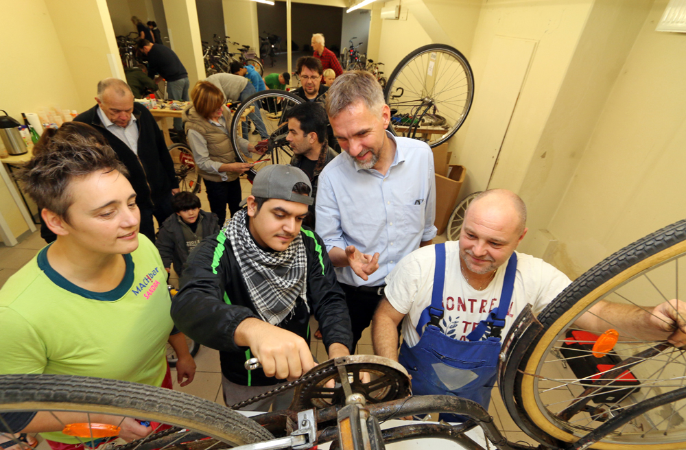 Bischof Jan Janssen (Zweiter v.r.) beim Besuch einer Fahrradwerkstatt, in der Flüchtlinge arbeiten