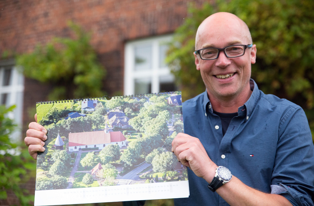 Pastor Matthias Goltz mit dem Kalender, der die Eiderstedter Kulturlandschaft zeigt