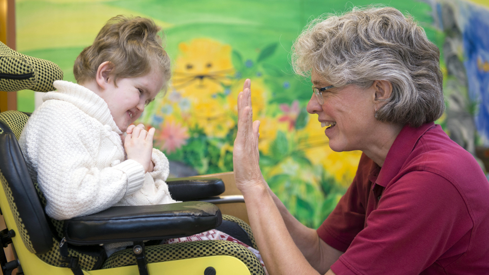 Krankenschwester Ulrike Senn klatscht mit der kleinen Alina ab