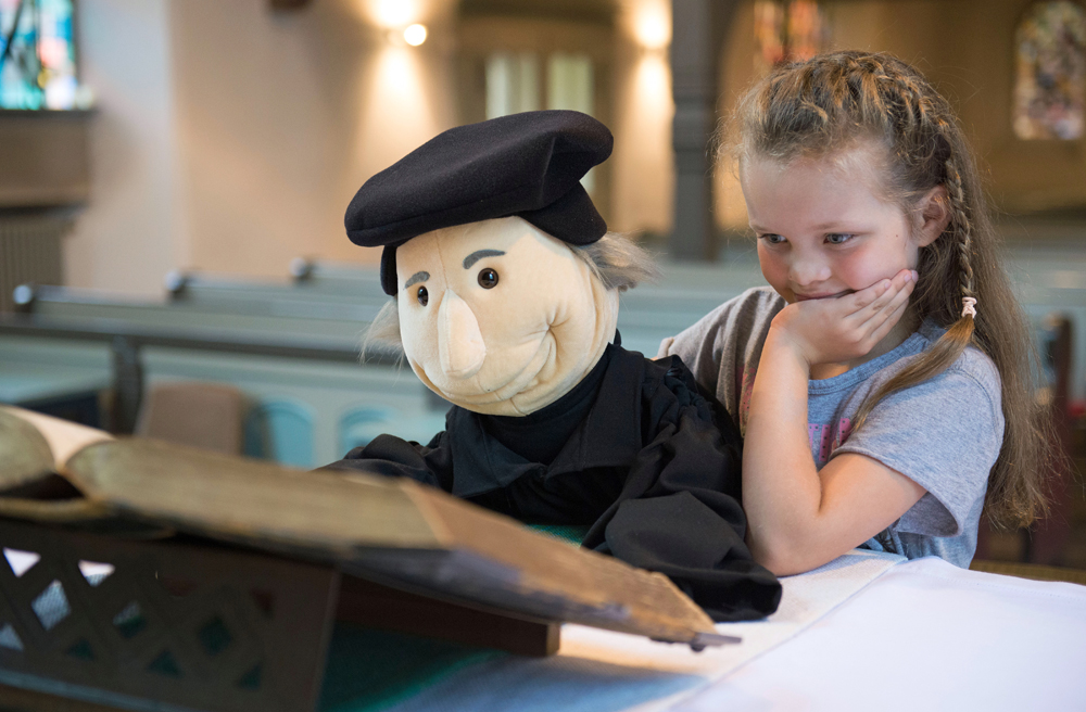 So macht Kirche Spaß: ein kleines Mädchen mit einer Luther-Handpuppe (Symbolbild)