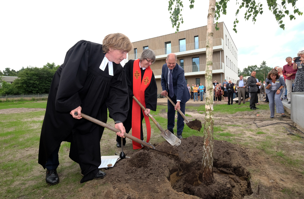 Pastor Oliver Spies und Pastorin Corinna Peters-Leimbach pflanzen zusammen mit Bürgermeister Olaf Scholz einen Baum