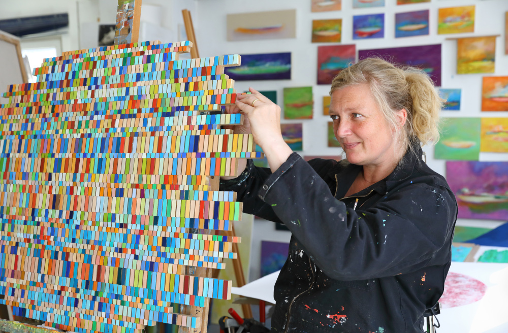 Die Künstlerin Susanne Nothdurft arbeitet an einer Collage aus farbigen Feldern.