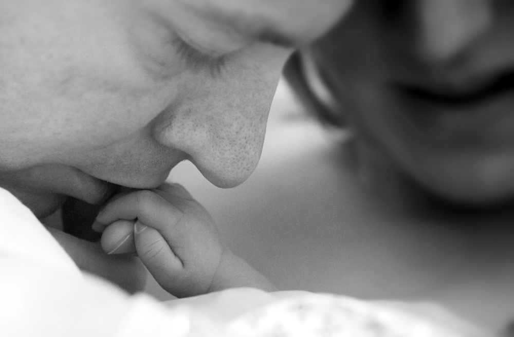 Ein Vater küsst die Hand seines totgeborenen Babys, fotografiert von der Initiative "Dein Sternenkind"