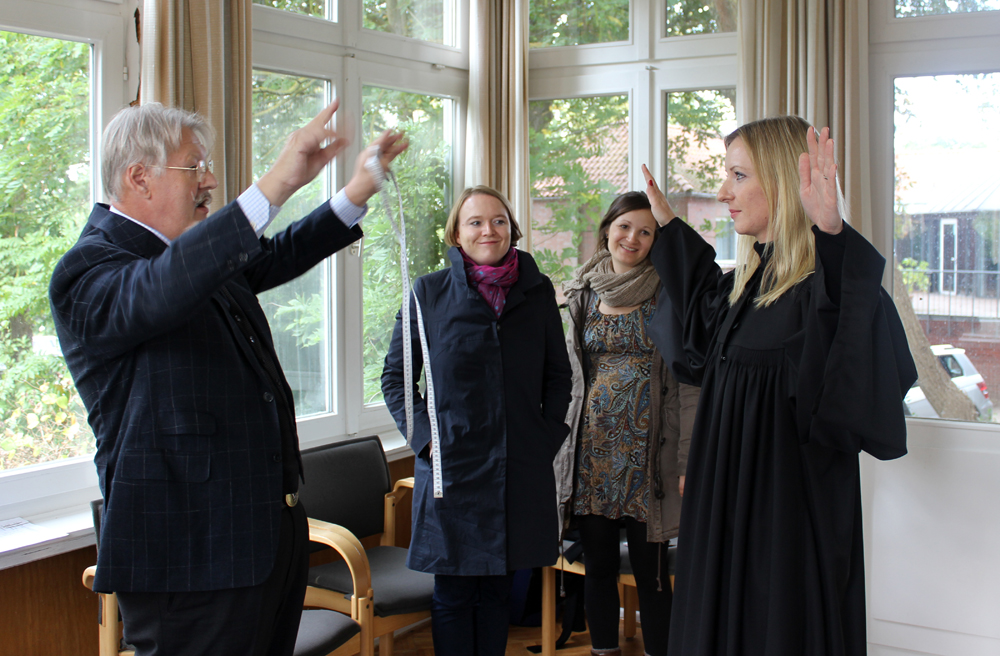 Vikarin Anna Cornelius hat einen Muster-Talar übergezogen, Schneider Reinhard Albrecht schaut genau hin