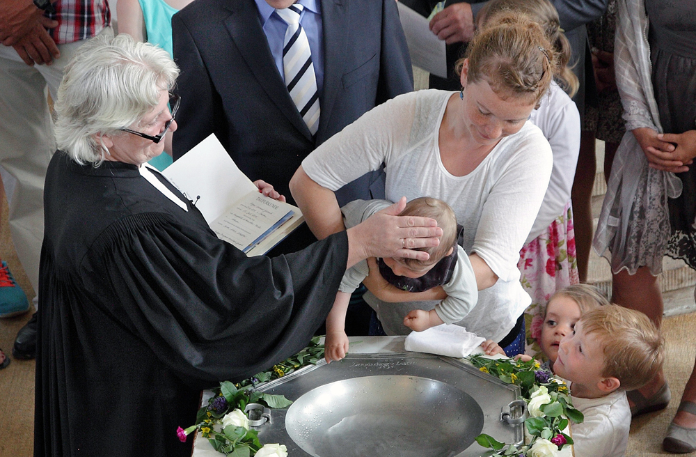 Eine Pastorin tauft ein Baby