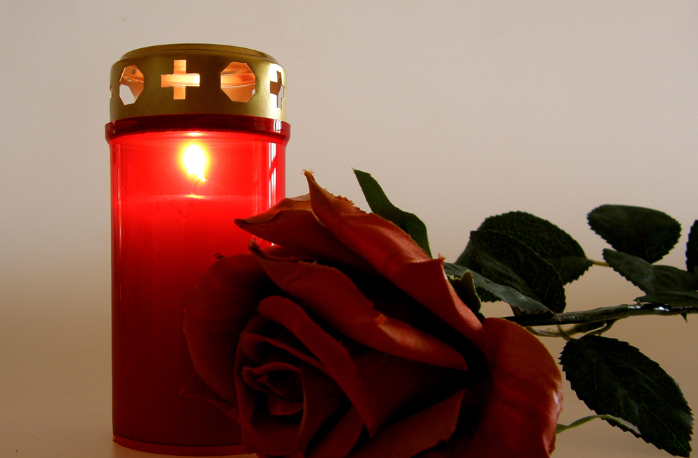 Kerze und Rose als Zeichen der Trauer (Symbolbild)