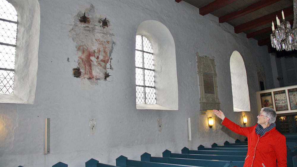 Gudrun Fuchs zeigt auf die Wandmalerei