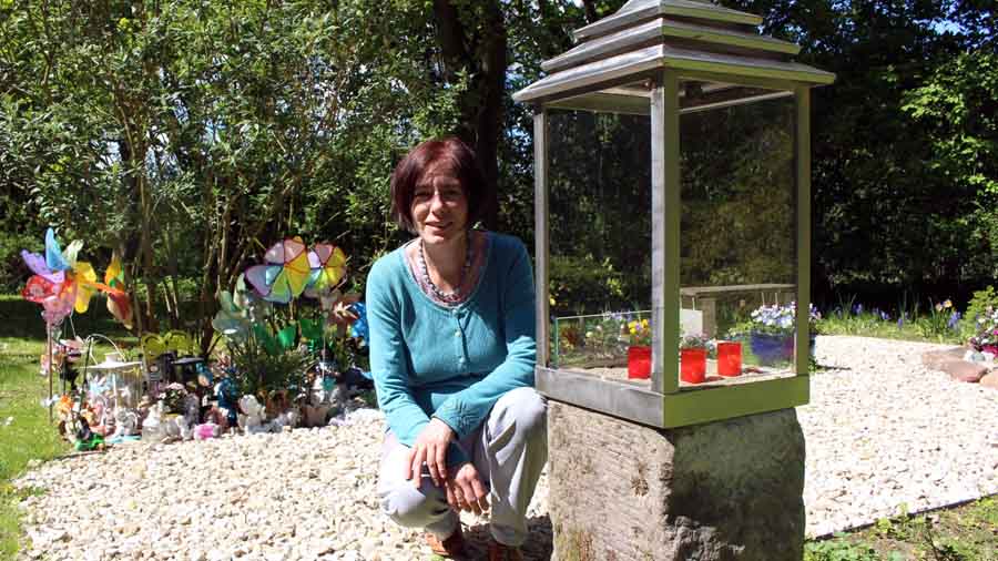 Pastorin Brita Bartels an der Stätte für still geborene Kinder, einem eigenen Bereicht auf dem Friedhof mit Blumen und Spielzeug