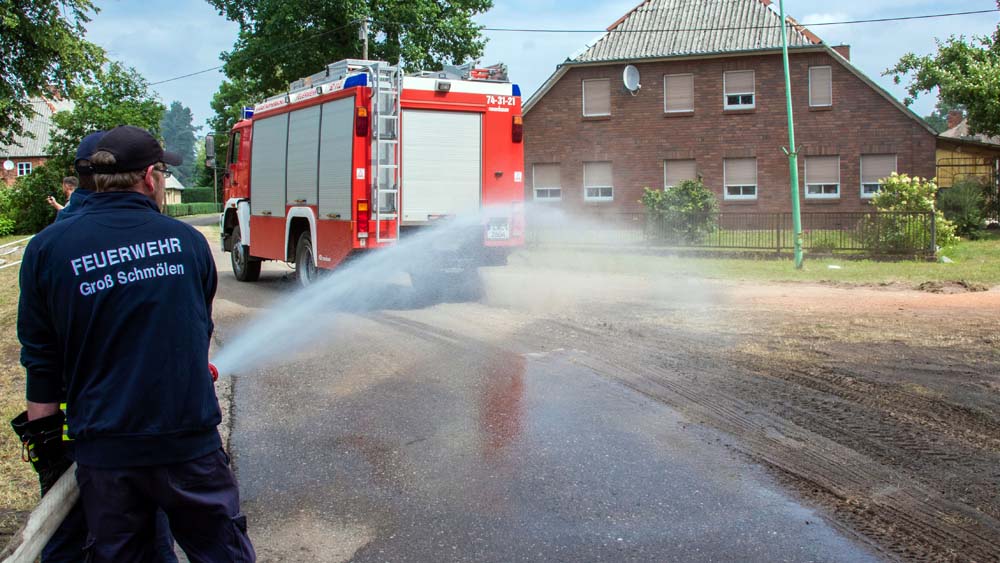 Feuerwehrleute verteilen Wasser in Alt Jabel, um die Wege feucht zu halten