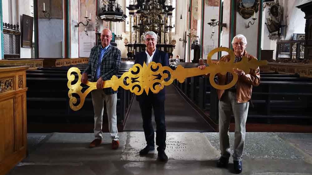 Joachim Glowe, Förderverein der historischen Bausubstanz von St. Jakobi, Pastor Lutz Jedeck und Jo Böcher, Vorsitzender des Fördervereins, mit einem der abmontierten Zeiger (v.l.)