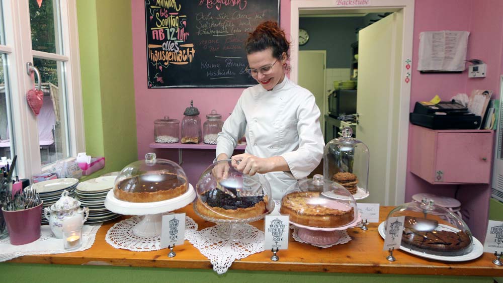 Eva Radieschen präsentiert Kuchen in ihrem Café