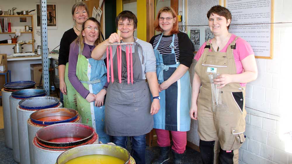 Die jungen Frauen aus dem Kerzenatelier der Greifswalder Greifenwerkstatt mit Werkstattleiterin Karola Wabnitz (li.) vor den bunten Wachstöpfen