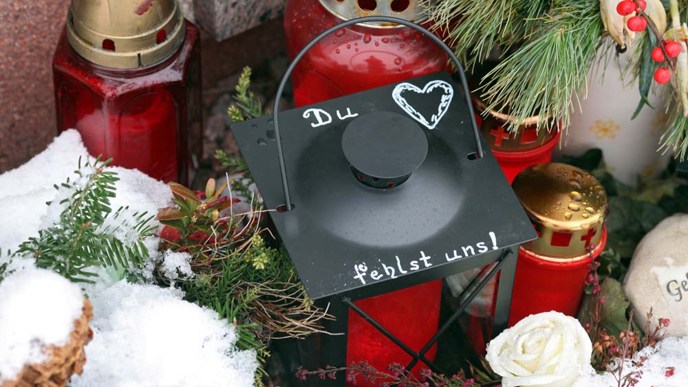 Kerzen im Schnee auf einem Friedhof