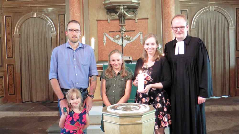Michaela Bödecker mit ihrer Familie in der Engelbosteler Kirche. Ihre älteste Tochter Manja Lu hat für sie die Taufkerze angezündet. Mit dabei: Pastor Rainer Müller-Jödicke