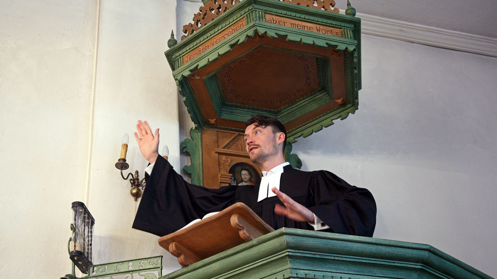 Ein Pastor steht auf einer Kanzel und predigt