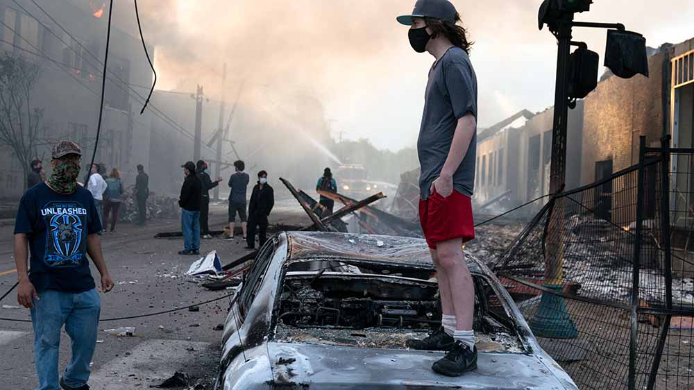 Gewalt in Minneapolis: Ein Mann steht auf einem ausgebrannten Auto