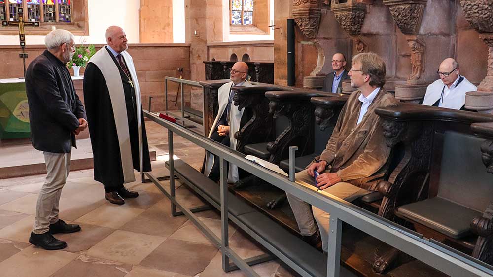 Ingenieur Jürgen Götz (li.)  und Abt Eckhard Gorka (Mitte) stellen das beheizbare Chorgestühl vor