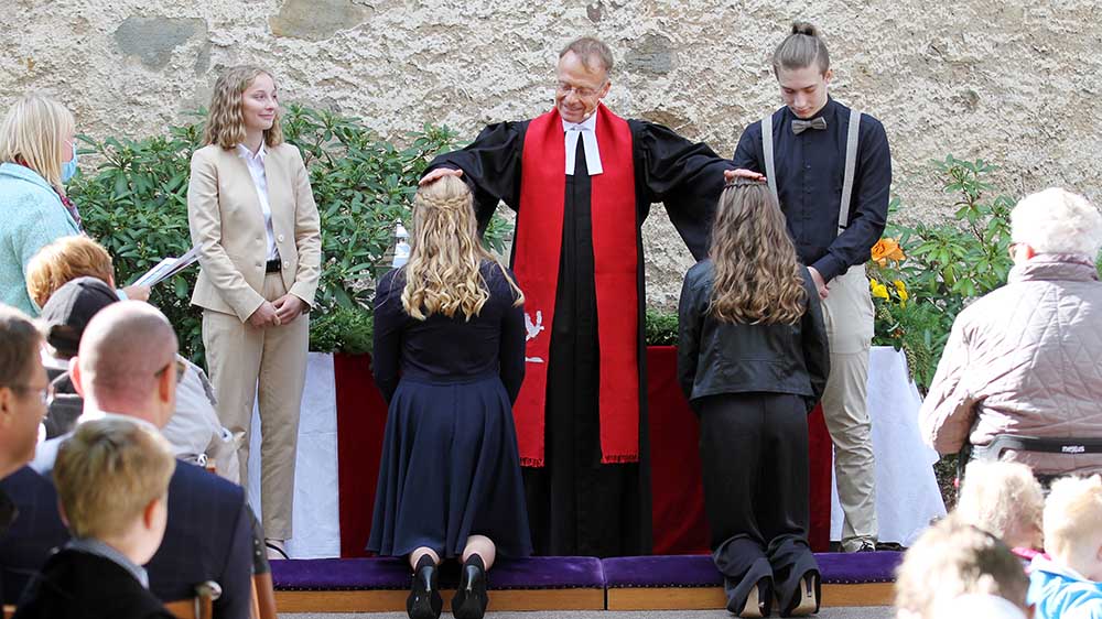 Pastor Sönke von Stemm segnet die Jugendlichen unter freiem Himmel ein