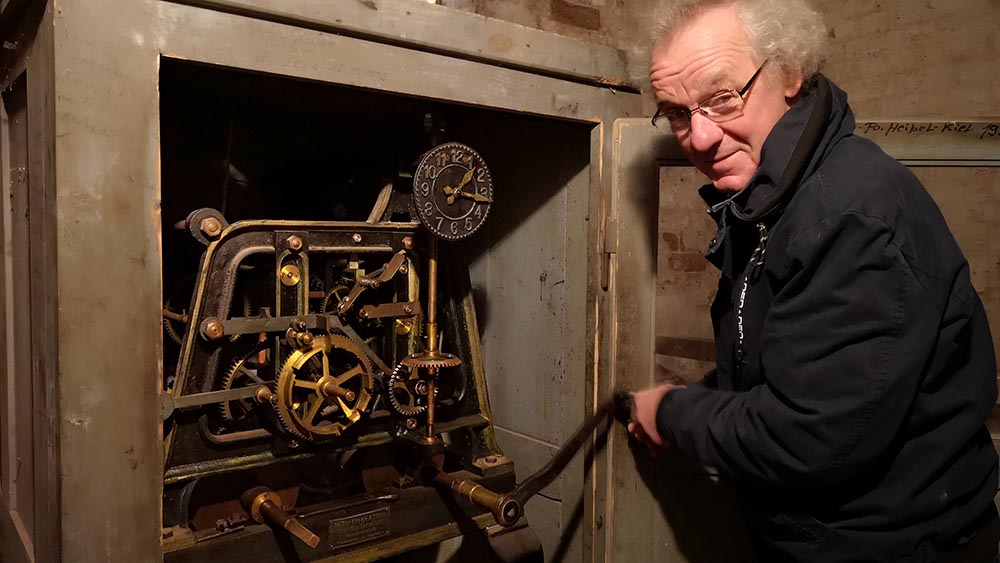 Pastor Martin Krumbeck dreht am Werk der Turmuhr – und die Zeiger bewegen sich zurück