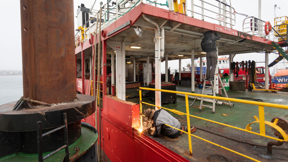 Das Schiff liegt eingekeilt zwischen Kaimauer und Schwimmkran im Hafen von Rostock. Philipp Reiss/epd