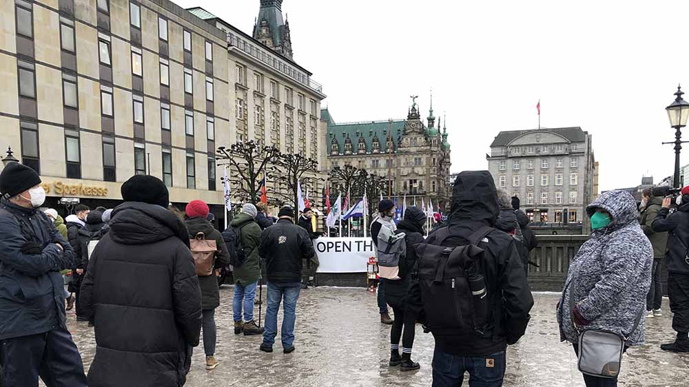 Vor dem Rathaus halten etwa 50 Menschen eine Mahnwache