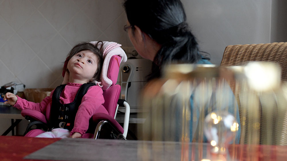 Emily in ihrem speziellen Stuhl, beobachte von Mutter Sandra