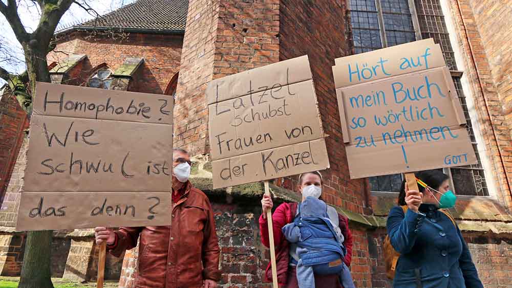 Vor der Martinikirche halten Demonstranten im April 2021 Plakate hoch
