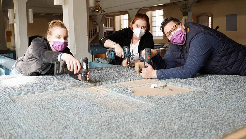 Mit der Teamerin Michelle Praman arbeiten die Pastorinnen Ellen und Stefanie Radtke (v.l.) in der Kirche von Eime an dem Kreuz