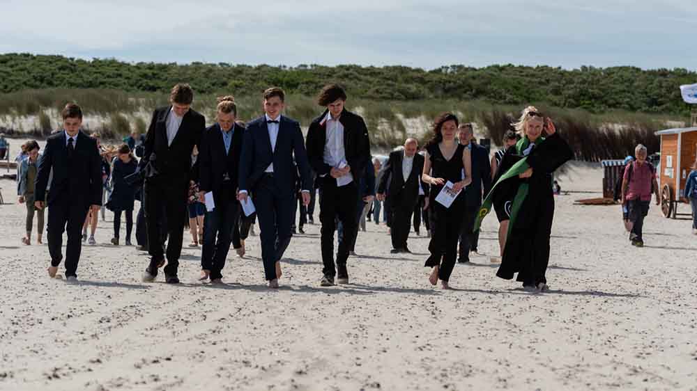 Über die Dünen laufen Konfirmanden und Pastorin zum Strand