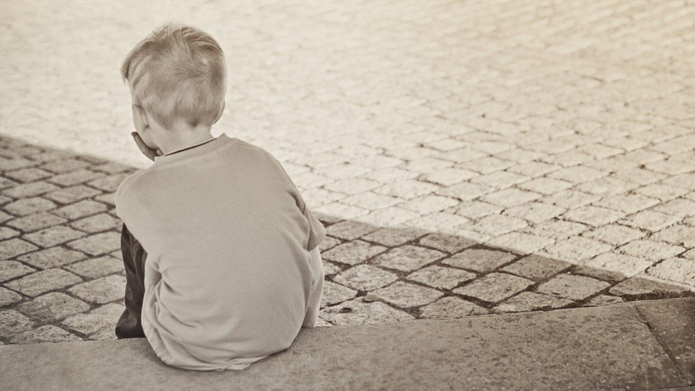 Einsames Kind vor einem Hauseingang (Symbolbild)