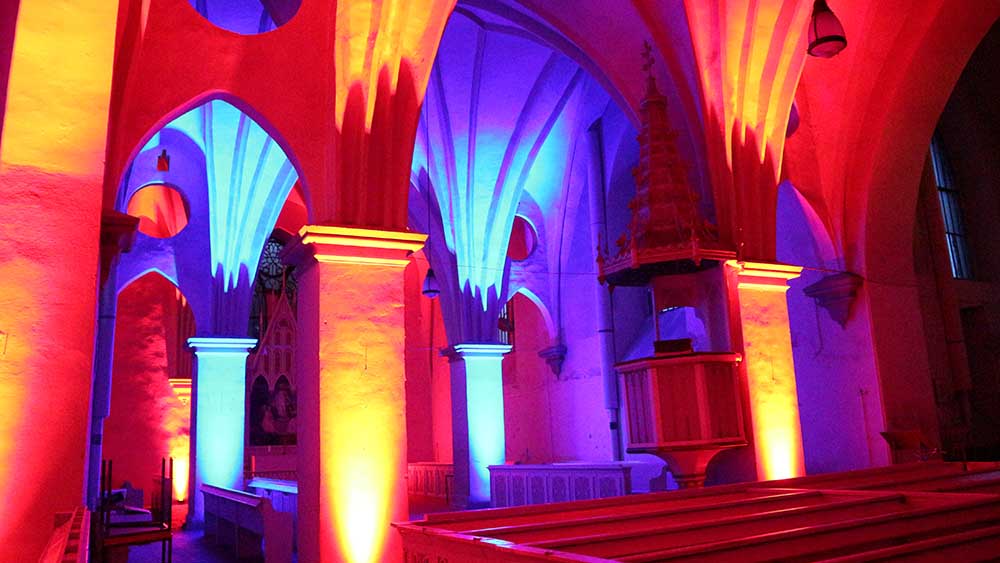 Innenraum der Kirche, der in rotes und violettes Licht getaucht ist