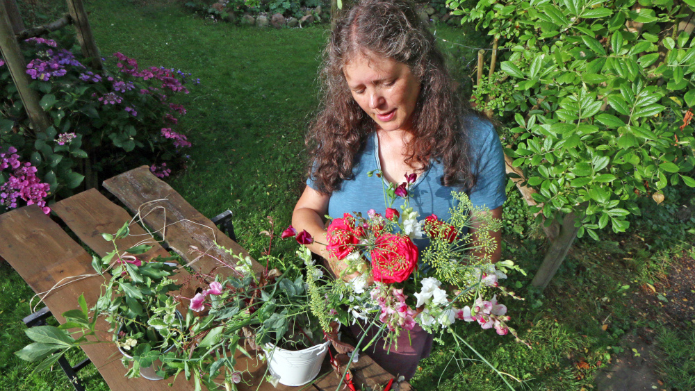 Claudia Werner bindet einen Blumenstrauss in ihrem Garten in Bremen (Foto vom 27.07.2021). Claudia Werner hat sich als Blumenbaeuerin selbststaendig gemacht. In ihrem “kleinen wilden Garten” erntet sie auf gut 1.000 Quadratmetern fuer Naturstraeusse, Gestecke und saisonale Kraenze, die sie in der Stadt ueber Unverpacktlaeden wie die “Fuellerei” oder den Hofladen der Solidarischen Landwirtschaft verkauft. (Siehe epd-Feature vom 09.08.2021)