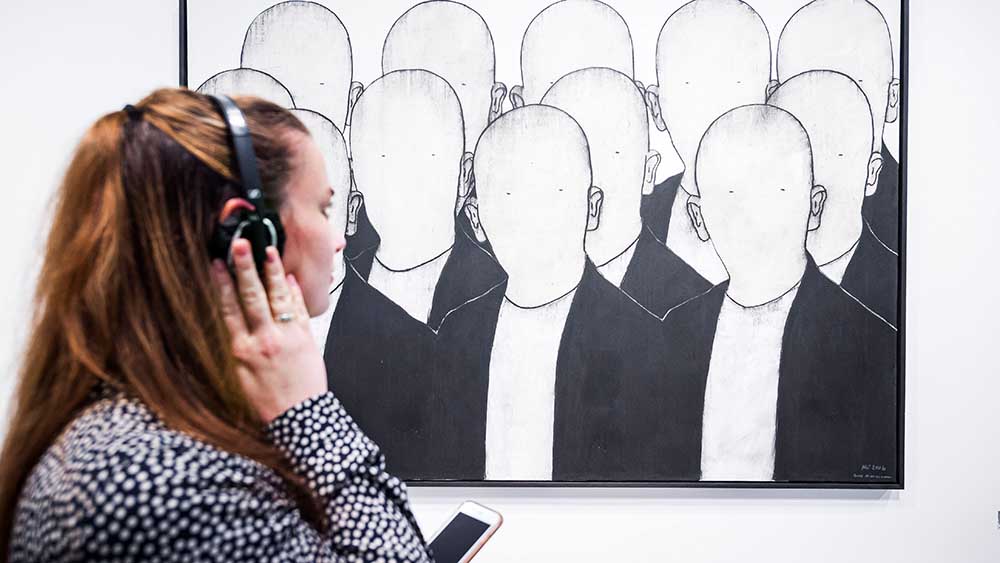 Eine Besucherin hört die Musik für dieses Bild von Max Neumann