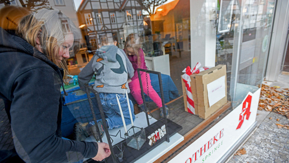 Diakonin Janette Zimmermann dekoriert mit Joas (7) und Melea (5) ein Schaufenster fuer einen Adventskalender quer durch die Stadt Springe (Foto vom 22.11.2021). Wenn Janette Zimmermann in Springe bei Hannover unterwegs ist, kann sie zu vielen Haeusern eine Geschichte erzaehlen. Zimmermann sieht die Stadt mit den Augen ihrer Zielgruppe: der 25- bis 45-Jaehrigen, die haeufig den Kontakt zur Kirche verloren haben. Und genau das will die 37-Jaehrige aendern. Sie bezeichnet sich selbst als “Kirchenpionierin” und sucht nach neuen Wegen, wie die Kirche von morgen aussehen kann. (Siehe epd-Bericht vom 24.11.2021)