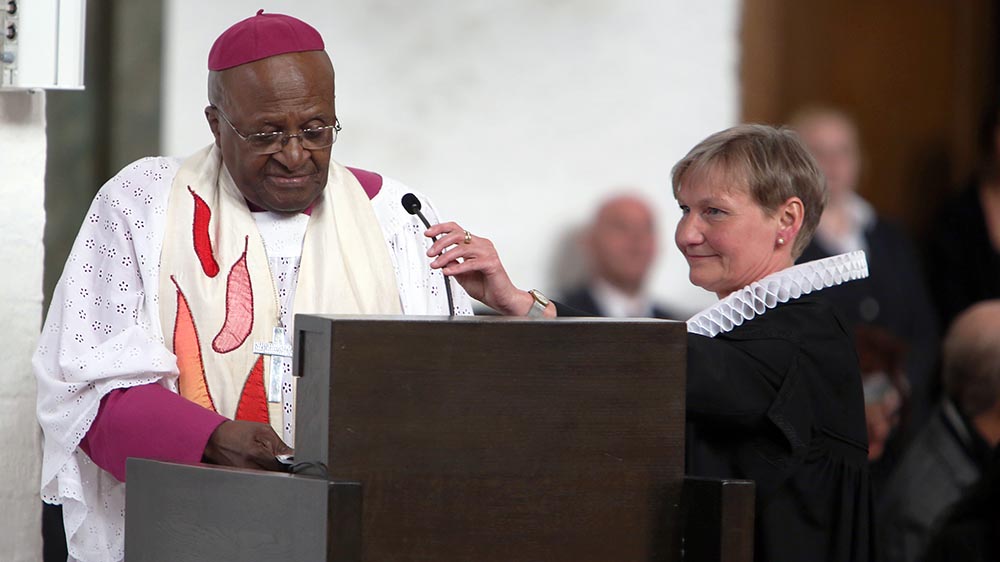 Im April 2015 spricht Tutu bei einem Dankgottesdienst für Philip Potter, den verstorbenen Generalsekretär des Weltkirchenrats. Hamburgs Bischöfin Kirsten Fehrs richtet das Mikrofon