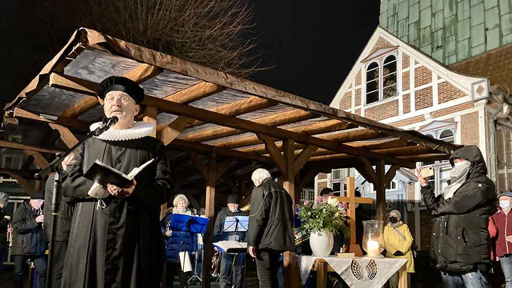 Pastor Andreas Baldenius spricht auf dem Platz vor der Kirche zur Gemeinde