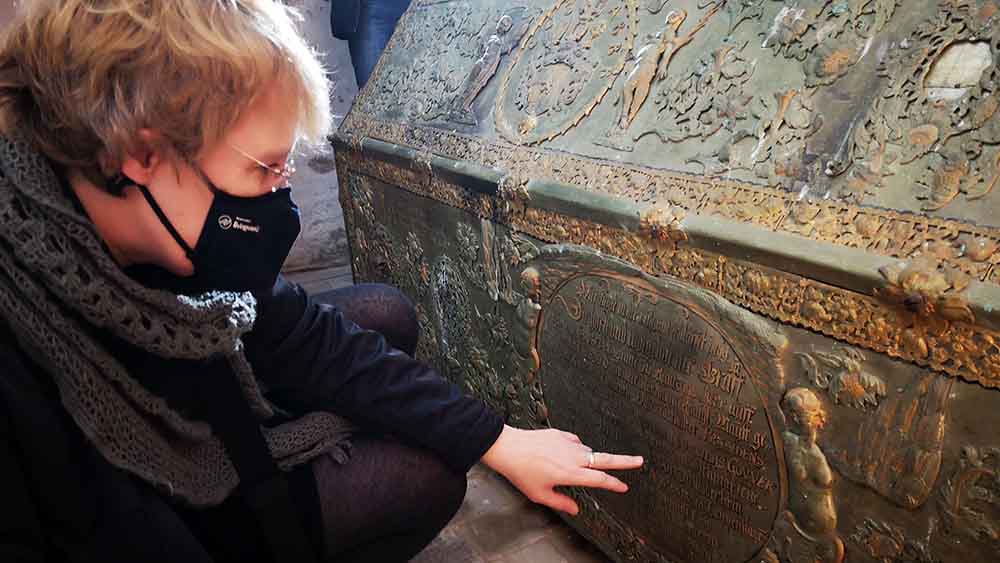 Pastorin Wiebke Bähnk zeigt auf die Inschrift eines Sargs