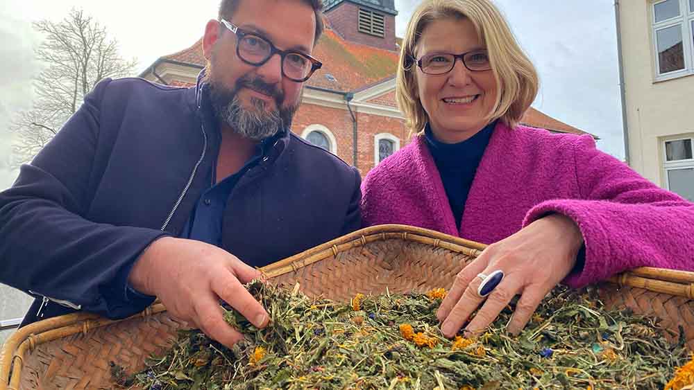 Der Friedhofsbeauftragte des Kirchenkreises, Bernd K. Jacob, und Pröpstin Frauke Eiben zeigen ein Substrat aus getrockneter Blumenwiese, Klee, Heu und Stroh vor, das bei einer Reerdigung verwendet werden kann 