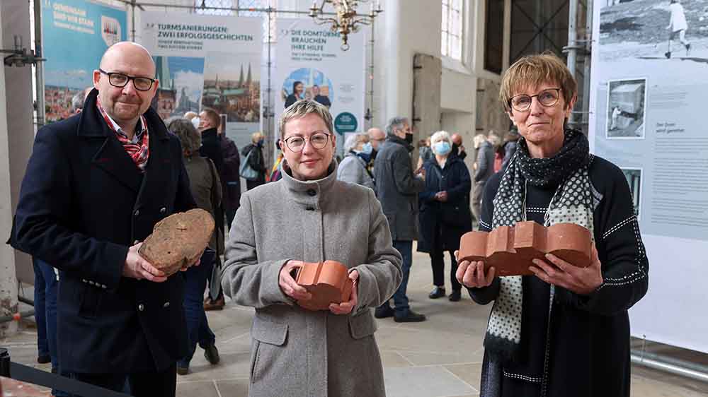 Der Ausstellungs-Designer Markus Endreß, Pröpstin Petra Kallies und Projektleiterin Cornelia Schäfer zeigen Domsteine aus unterschiedlichen Jahrhunderten