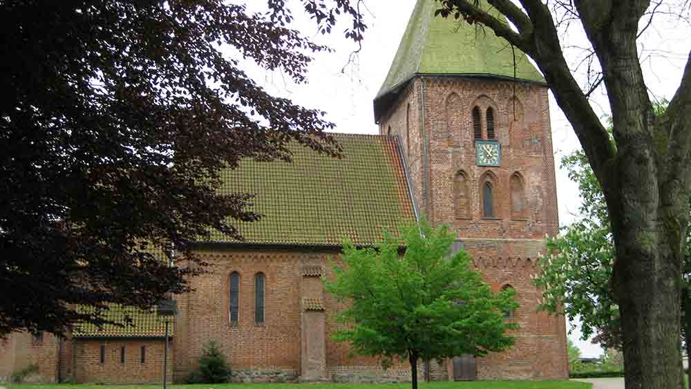 Backsteinkirche von Außen mit grünem Rasen