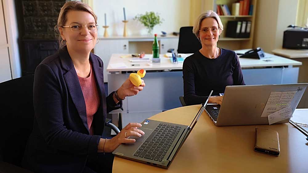 Birgit Lunde (li.) und Anja Ahrens beantworten Fragen. Auf der Gummiente steht der QR-Code des Whatsapp-Kanals