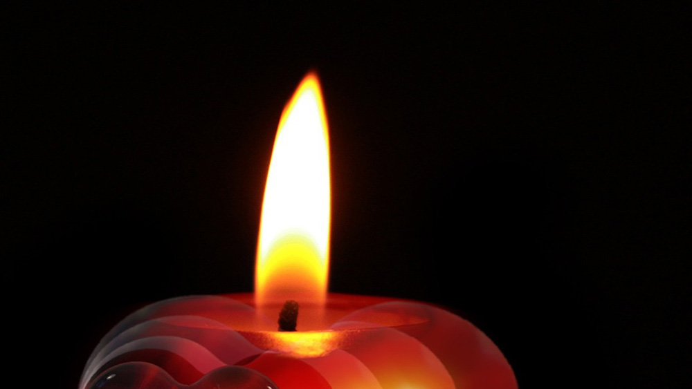Kerze brennt vor schwarzem Hintergrund